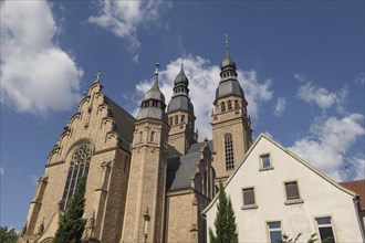 Gothic church with towers next to a modern building under a blue sky, speyer, germany