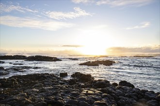 Sunrise over the sea with gentle waves. Sandy beach with lava rocks and blue water alternating with