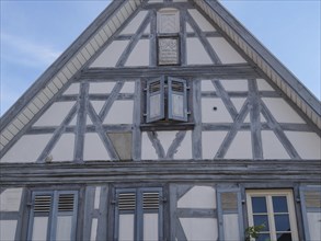 Half-timbered house with grey wooden structure and blue shutters under a clear sky, Kandel,