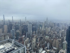 Hazy view of a city with numerous skyscrapers and tall buildings under a cloudy sky, New York, USA,