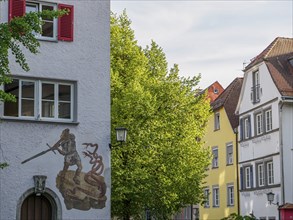 Historic building with mural of a knight and dragon surrounded by trees in an old town, lindau,