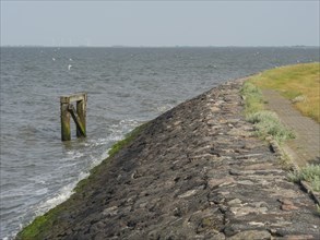 A stony path runs along the seashore, waves crash against the coast, hallig hooge,