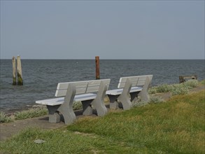 Several grey benches stand on the shore overlooking the sea, hallig hooge, schleswig-holstein,