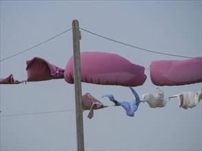 Colourful items of clothing hang on a rural washing line in the wind against the blue sky, hallig