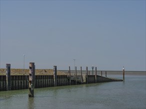 Quiet harbour with wooden piles and a clear sky over the sea, hallig hooge, schleswig-holstein,