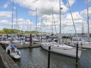 Sailboats in the harbour under a clear sky with few clouds and calm water, Eckernforde,