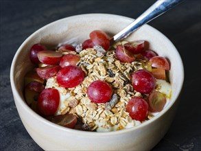 Fresh homemade muesli with organic red grapes and oat flakes, close-up
