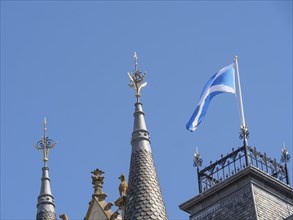 Towers of a building with a Scottish flag on the roof against a clear blue sky, Inverness,