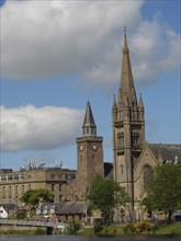 A soaring church spire and clock tower against a background of clouds and blue sky, Inverness,