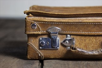 An old suitcase on the floorboard, old shabby leather portable suitcase for travel trip on floor
