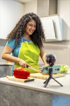 Vertical photo of a latin young female pretty live streamer cooking healthy food online