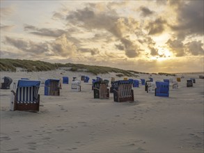 Extensive beach with colourful beach chairs at an atmospheric sunset, Juist, North Sea, Germany,
