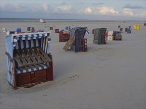 Scattered beach chairs on the wide, sandy beach under a clear sky, Juist, North Sea, Germany,