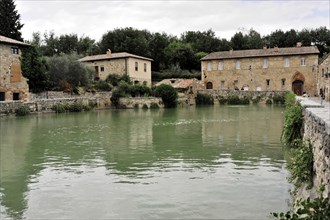 Tuscany, Italy, Europe, A quiet pond in a village with stone houses, trees and green water in a