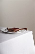 Roast leg of goose on a linen tablecloth