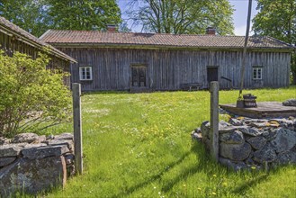 Rustic old farm with wooden house a water well and a gate by a stone wall in the swedish