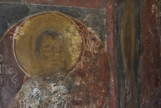 Faded mural painting of a holy person in a church, slightly damaged and weathered, Byzantine chapel