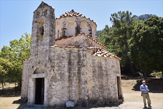 A small, old church with a stone bell tower, surrounded by trees under a blue sky, Byzantine chapel