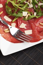 Carpaccio on a plate with parmesan and pine nuts