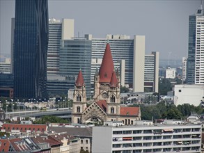 A church with red roofs in front of modern skyscrapers in an urban environment on a sunny day,