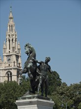 A graceful equestrian statue depicting a fighting horse with a historic Gothic clock tower in the