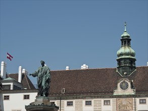 Historical monument with statue in front of a building with tower and clock, Vienna, Austria,