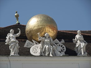 Detail of sculptures next to a golden ball on a roof in front of a blue sky, Vienna, Austria,