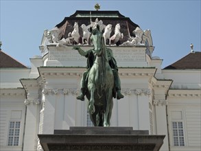 Equestrian statue in front of a magnificent baroque building with decorative elements, Vienna,