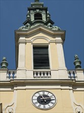 A baroque church tower with a clock and a yellow façade under a blue sky, Vienna, Austria, Europe