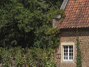 A brick house wall with a window and an ivy-covered garden, ochtrup, münsterland, germany