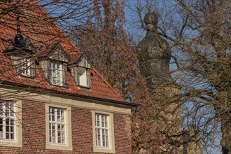 Old building with tiled roof and turrets in the background behind bare trees on a sunny day, gemen,