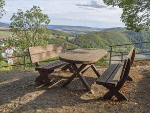 A wooden table with benches offers an idyllic view of the hilly landscape, Waldeck, Hesse, Germany,