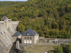 A large dam flanked by buildings and surrounded by autumn-coloured forest and trees, Waldeck,