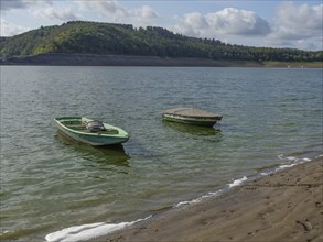 Two boats on a calm lake in front of a hilly landscape with a cloudy sky, Waldeck, Hesse, Germany,