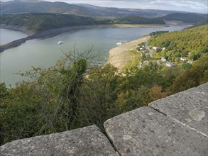 View of a river lined with hills and forests with a stone wall in the foreground, Waldeck, Hesse,