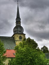 A tall church tower with clock against a dramatic, cloudy sky, Gothic architecture, Werl, North