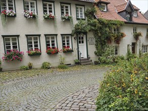 Half-timbered house with flowers on the windows and a cobbled street, Werl, North Rhine-Westphalia,