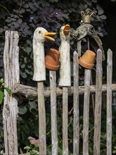 Rustic wooden fence with duck statues and upturned clay pots as decoration, SChermbeck North