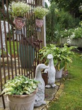 Garden area with duck sculptures, flower pots and plants next to a lattice fence, SChermbeck North