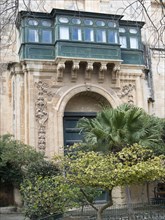Large green balcony and ornate stone gate of an old building, valetta, mediterranean sea, malta