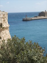 A rocky coast and a small lighthouse overlooking the calm sea, valetta, mediterranean sea, malta