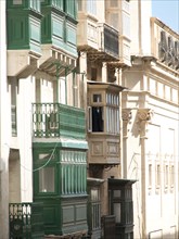 Several houses with existing wooden balconies painted in green and beige, valetta, mediterranean