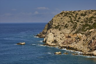 Cliff landscape by the sea with blue water and cloudy sky, Atavyros beach, near Monolithos village,