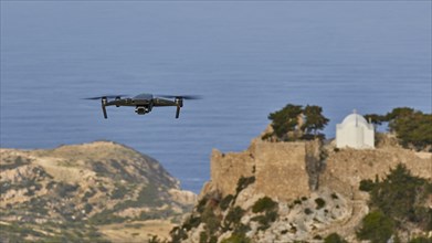 Drone flies over a castle ruin with chapel on a rock in front of the wide sea, Chapel of Saint