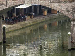 View of a canal with a bridge under which lies a quiet restaurant on the water, utrecht,