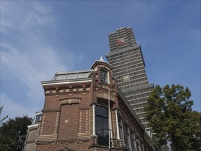 Modern tower rising into the sky behind a historic brick building, utrecht, Netherlands
