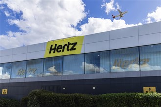 Hertz Car Rental at London Heathrow Airport with a plane flying over the building