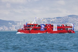 Supporters of the ruling AK party waving turkish flags on a red boat before presidential elections
