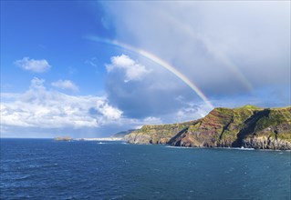 Colorful rainbow arching over the coastline of the azorean island San Miguel