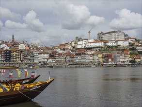 City view with river and boats, in the background historical buildings, a bridge and cloudy sky,